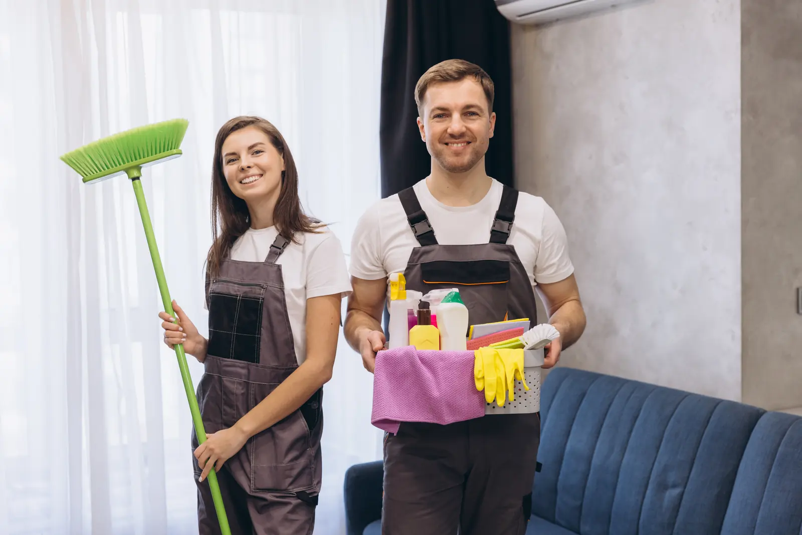 Lächelndes Reinigungsteam mit Besen und Reinigungsmitteln